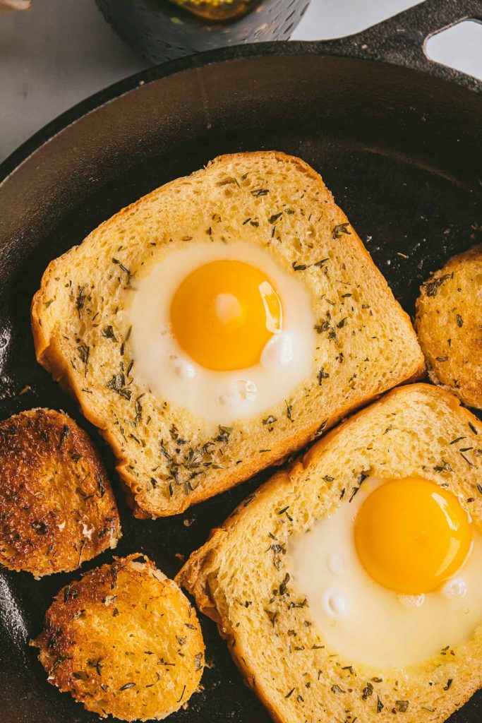 two slices of egg in a hole with texas toast in a cast iron skillet