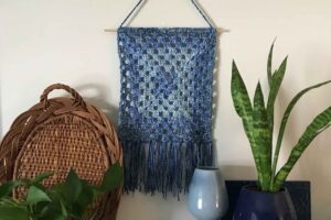 Wall art featuring blue and gray crochet textile.