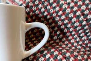 Coffee mug with a heart-shaped handle on a colorful woven fabric background.