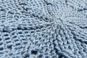 Close-up of intricate light blue crochet pattern by Juniper and Oakes.