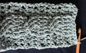Close-up of a textured, hand-knit blanket in soft gray yarn.
