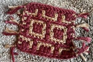 Handwoven textile with intricate geometric patterns in red and beige.