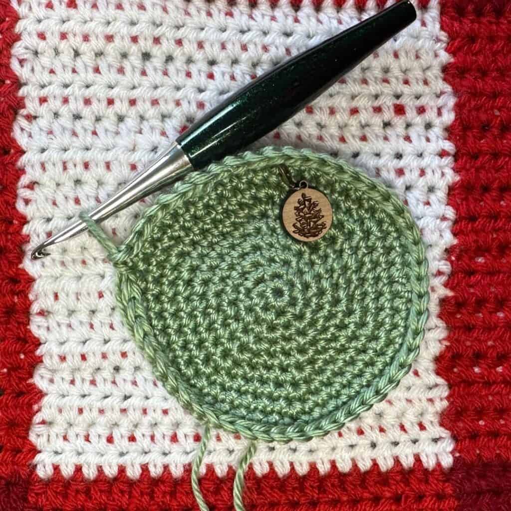 Handmade green alpine stocking crochet pattern with wooden charm.
