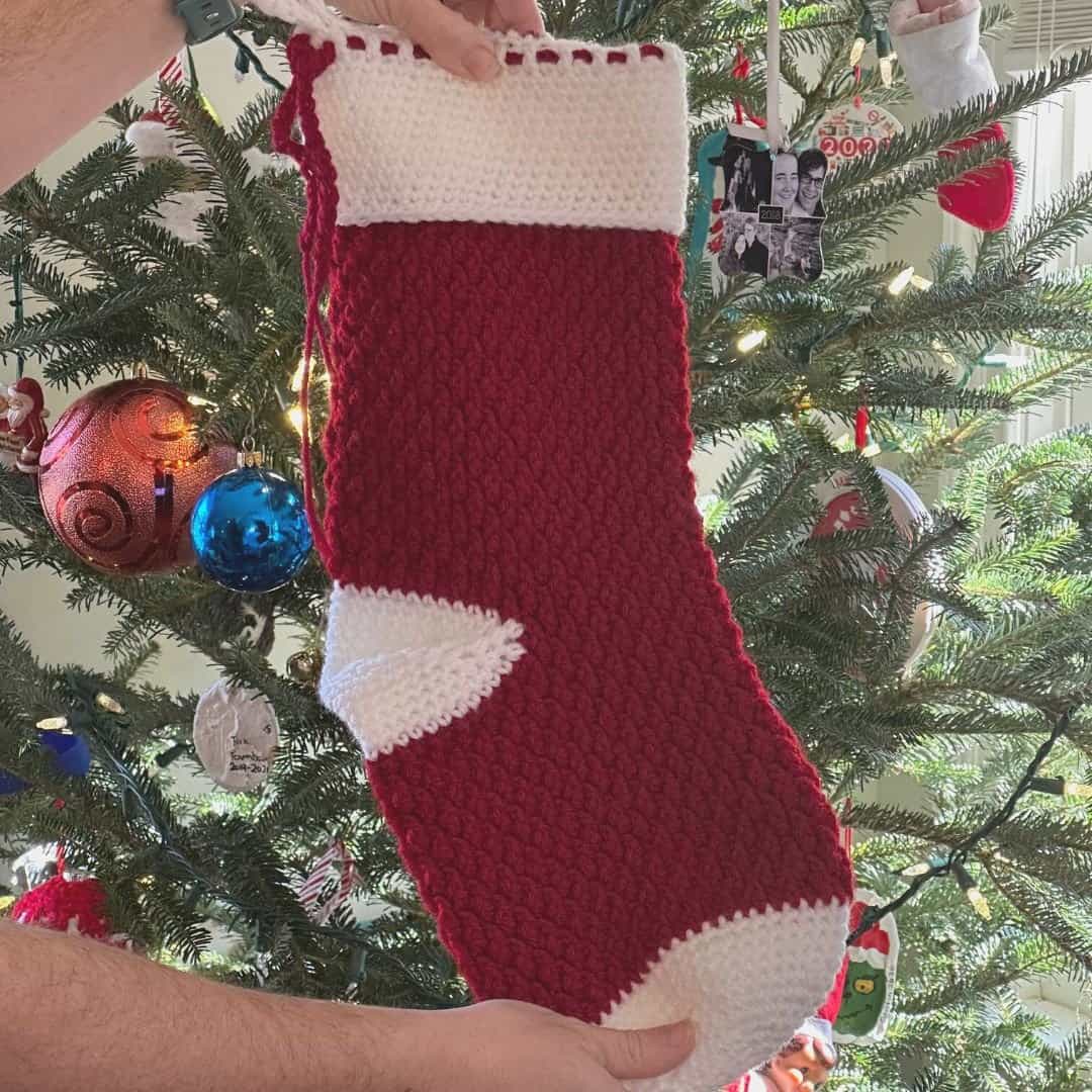 Cozy red and white Christmas stocking with textured crochet design, perfect for holiday decor.