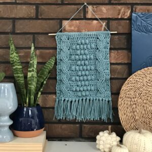 Decorative crochet wall hanging in blue with fringe detail.