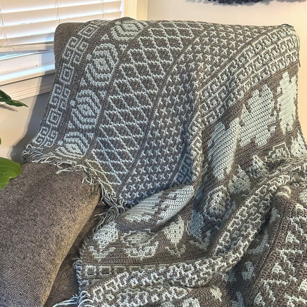 Decorative mosaic Afghan throw with intricate geometric and floral patterns in neutral tones.