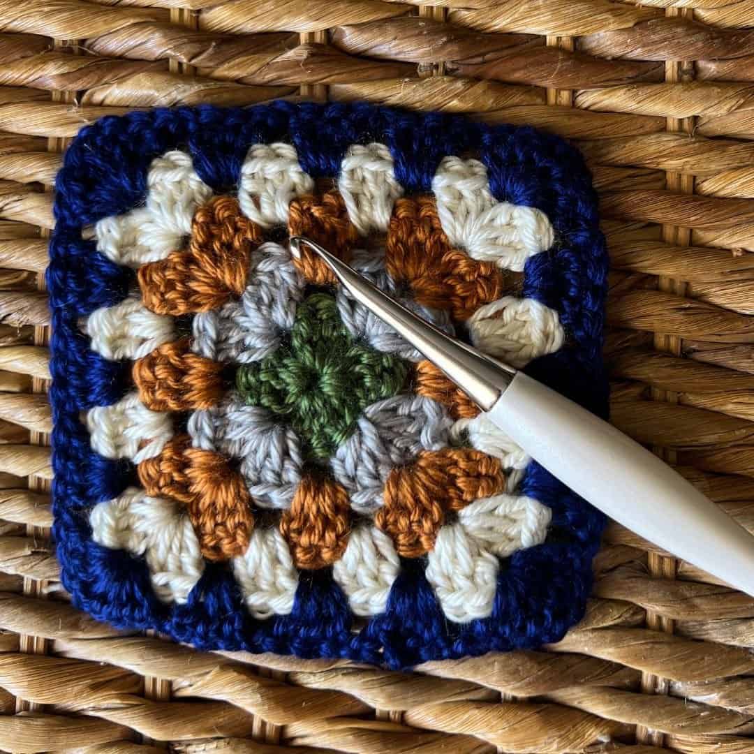 Vibrant multicolored granny square crochet with a crochet hook, celebrating International Granny Squ.