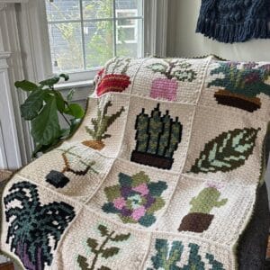 Decorative crochet blanket featuring diverse plant and flower patterns.