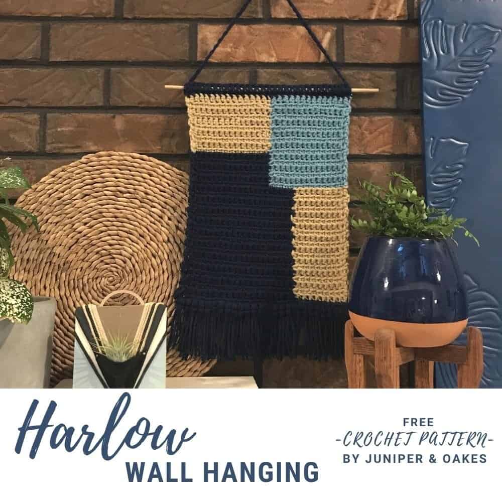 Handcrafted geometric wall hanging with beige, blue, and black yarns.