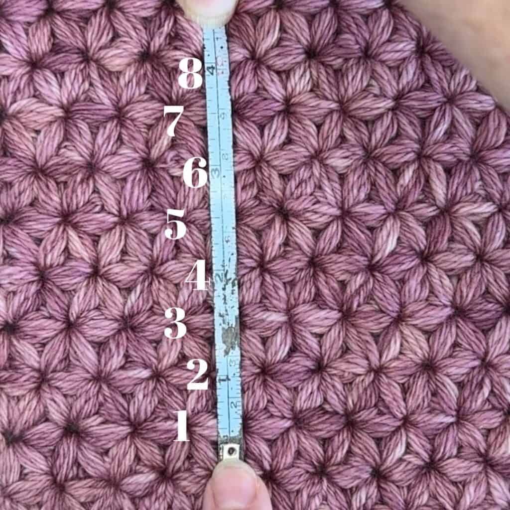 Up of pink textured knitted fabric with a measuring tape for size reference.