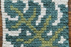 Handwoven textile featuring juniper and oak leaf patterns in green and blue tones.