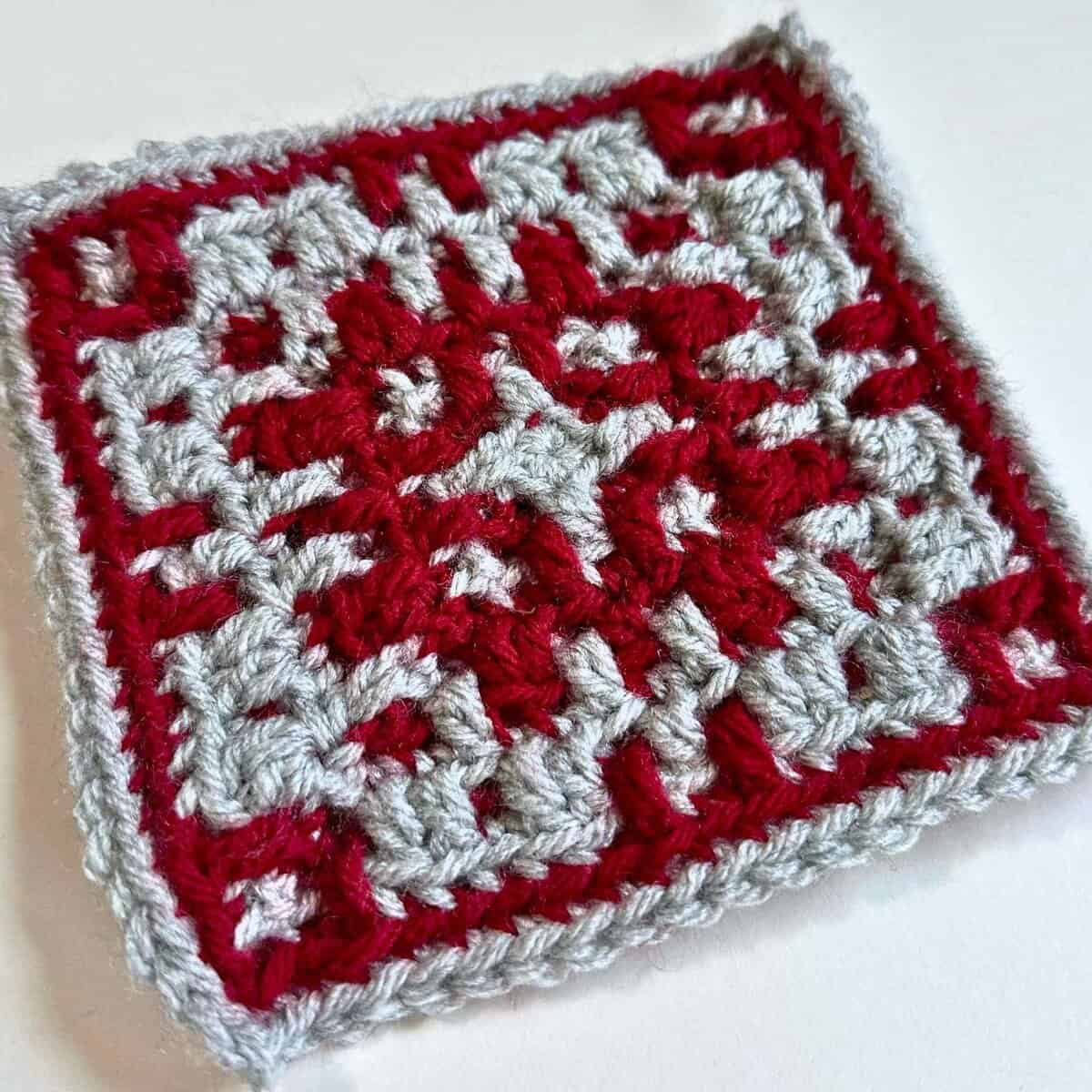 Crochet square featuring red and gray yarn, perfect for blankets or decorative projects.