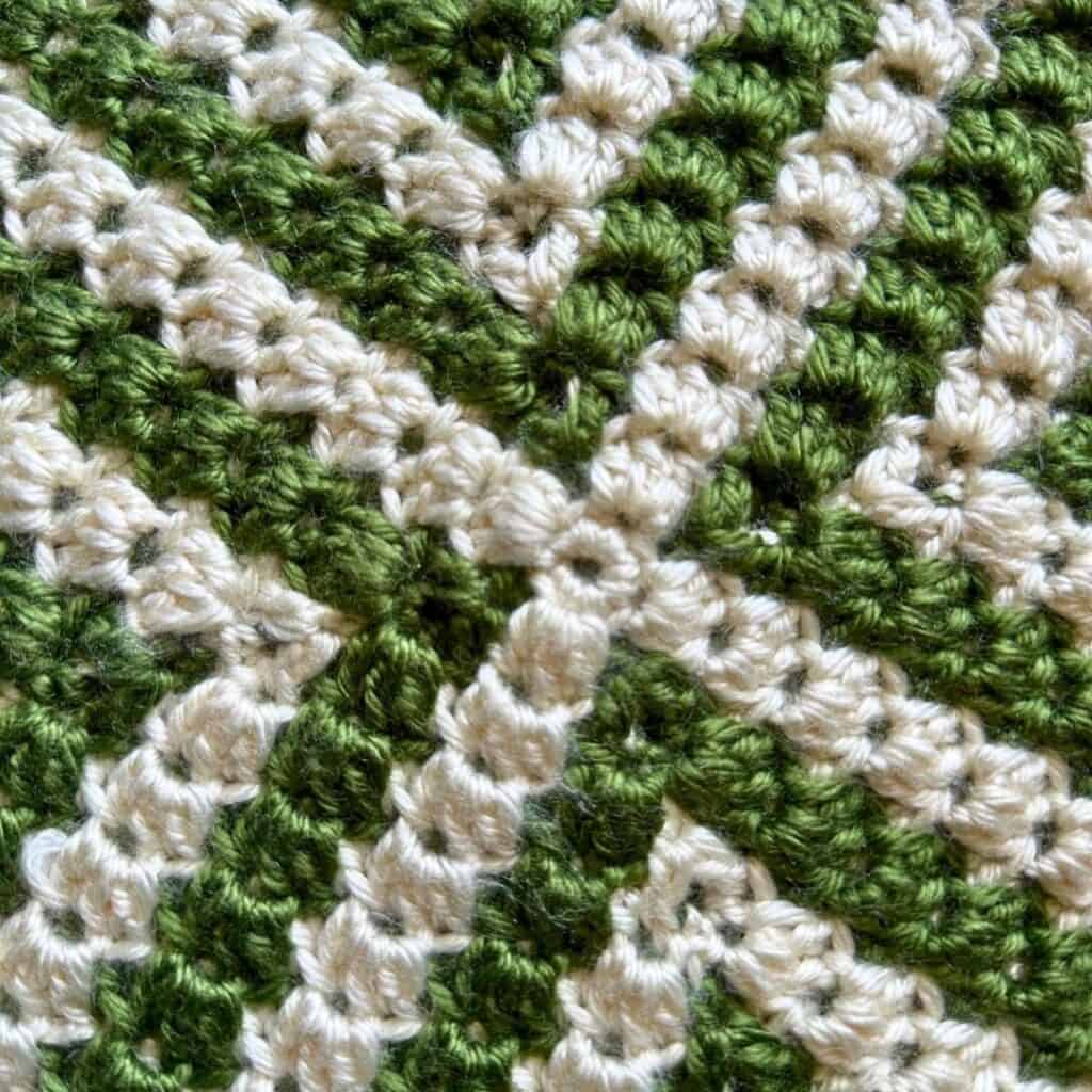 Close-up of a green and white crochet pattern with textured stitches.