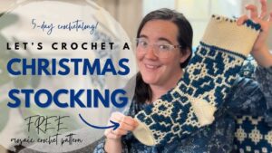 Woman holding a festive blue and cream crochet Christmas stocking.