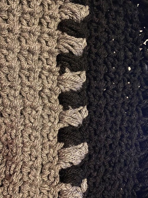 Crochet textured blanket featuring beige, gray, and black yarns, showcasing intricate craftsmanship.