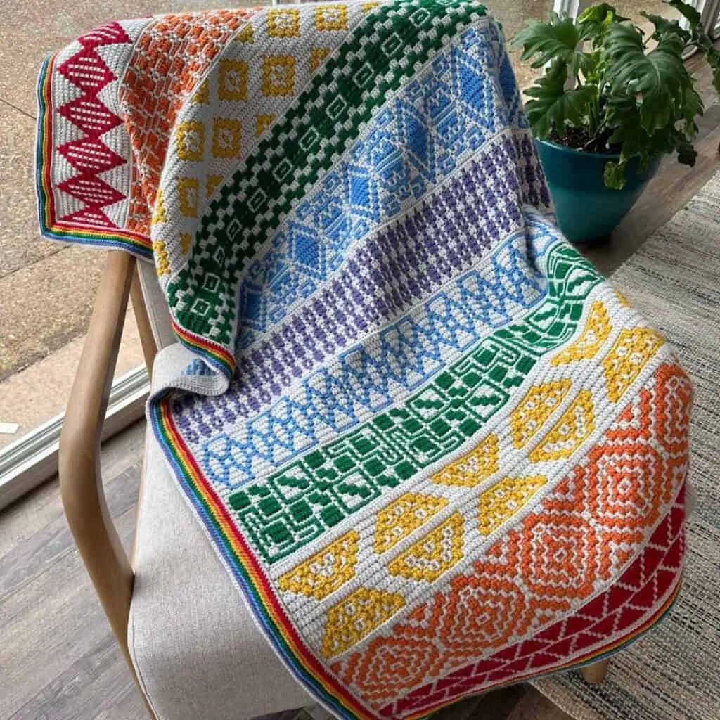 Colorful geometric mosaic crochet blanket draped over a chair.