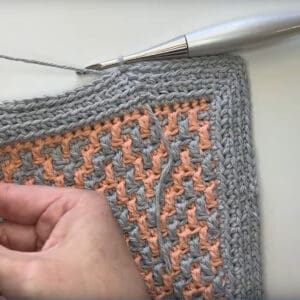 Close-up of crochet envelope border with peach and gray yarns.