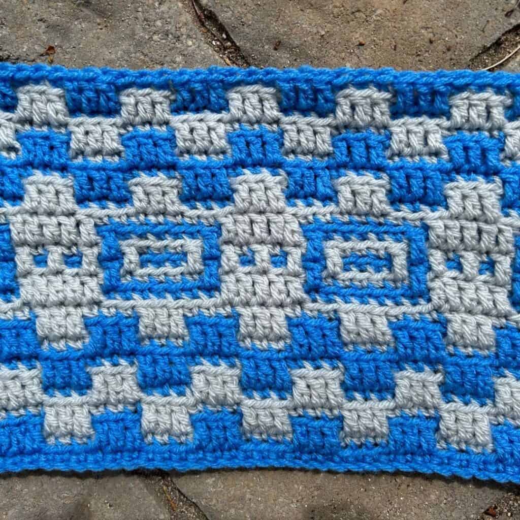 Close-up of a blue and gray geometric mosaic crochet blanket pattern.