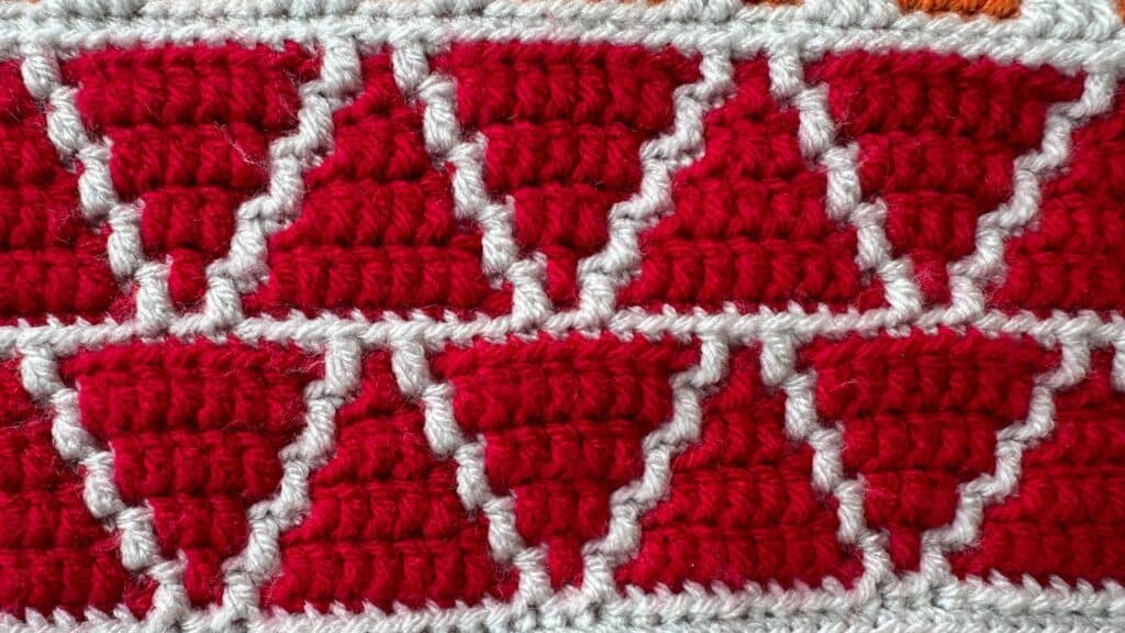 Close-up of red and white geometric mosaic crochet blanket pattern.