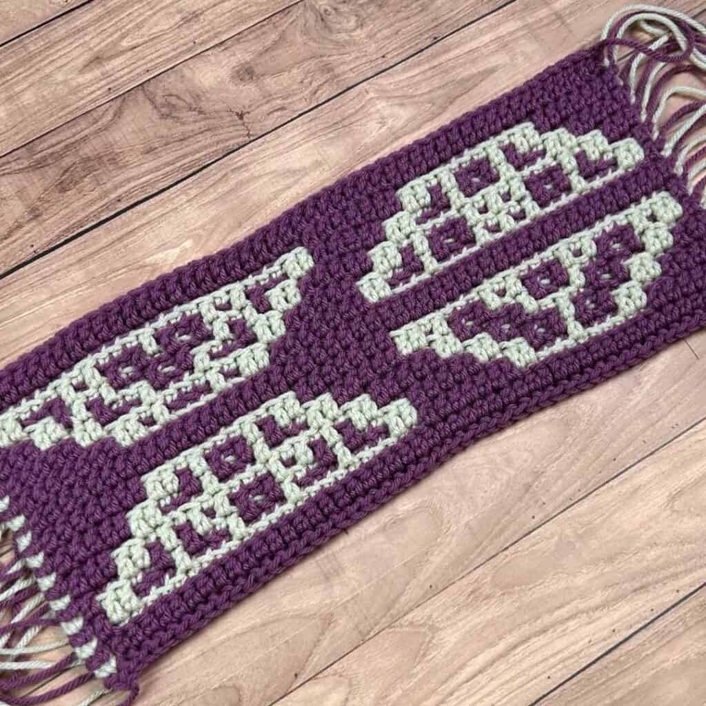 Geometric mosaic crochet blanket in purple and cream, handmade for cozy decor.