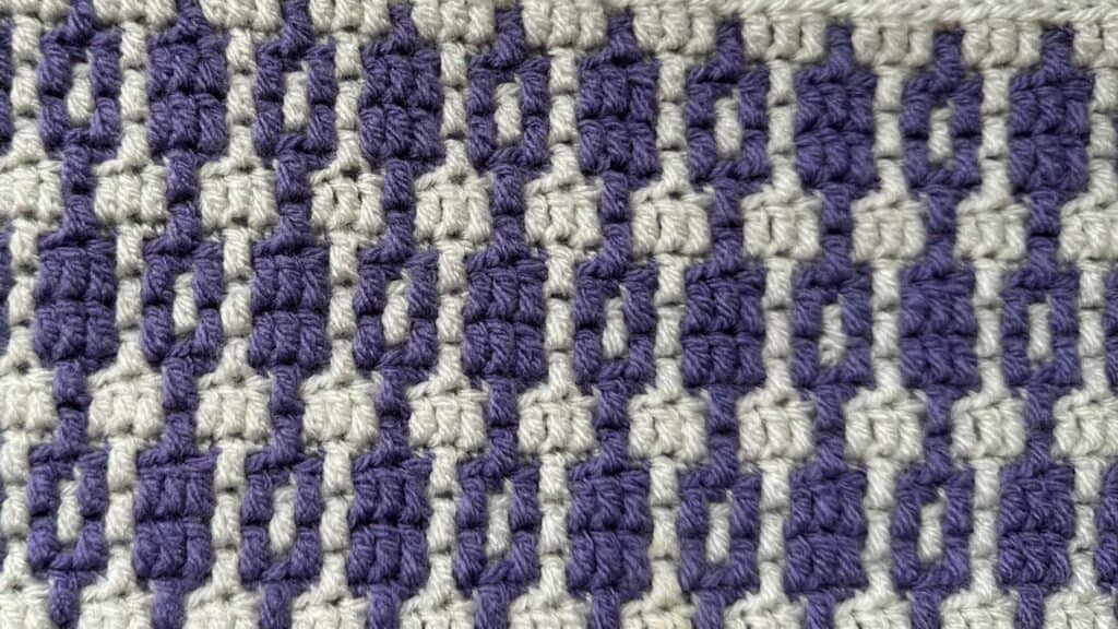 Geometric mosaic crochet blanket with purple and cream colors for crochet along.
