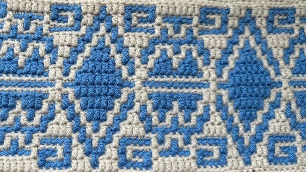 Up of a blue and beige geometric mosaic crochet blanket.