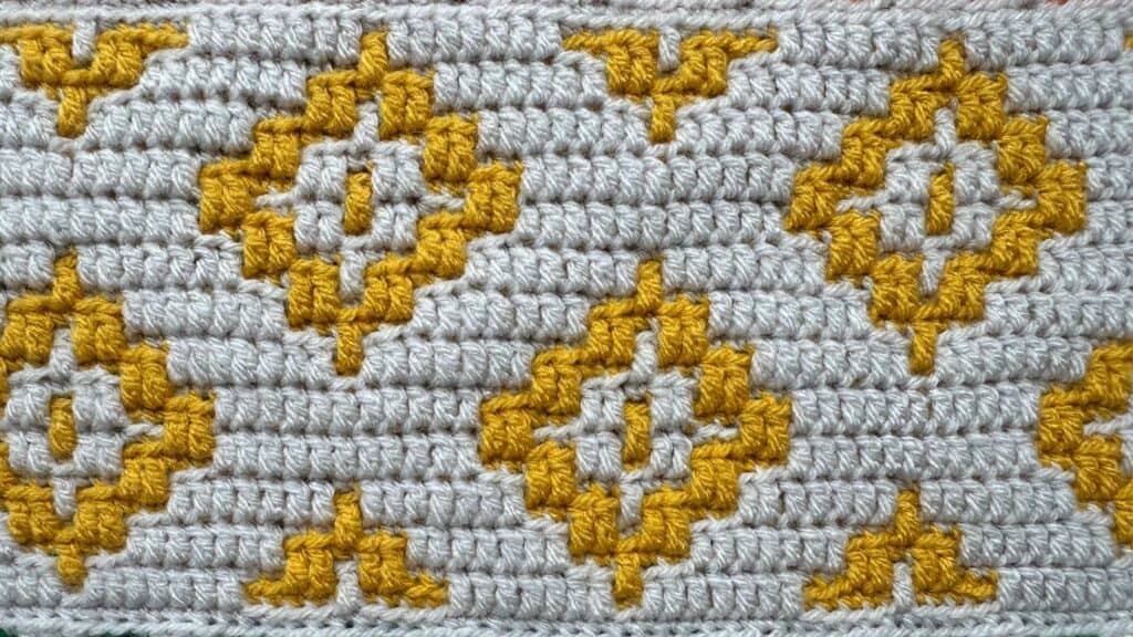 Geometric mosaic crochet blanket with yellow and white patterns, inspired by the CAL project.