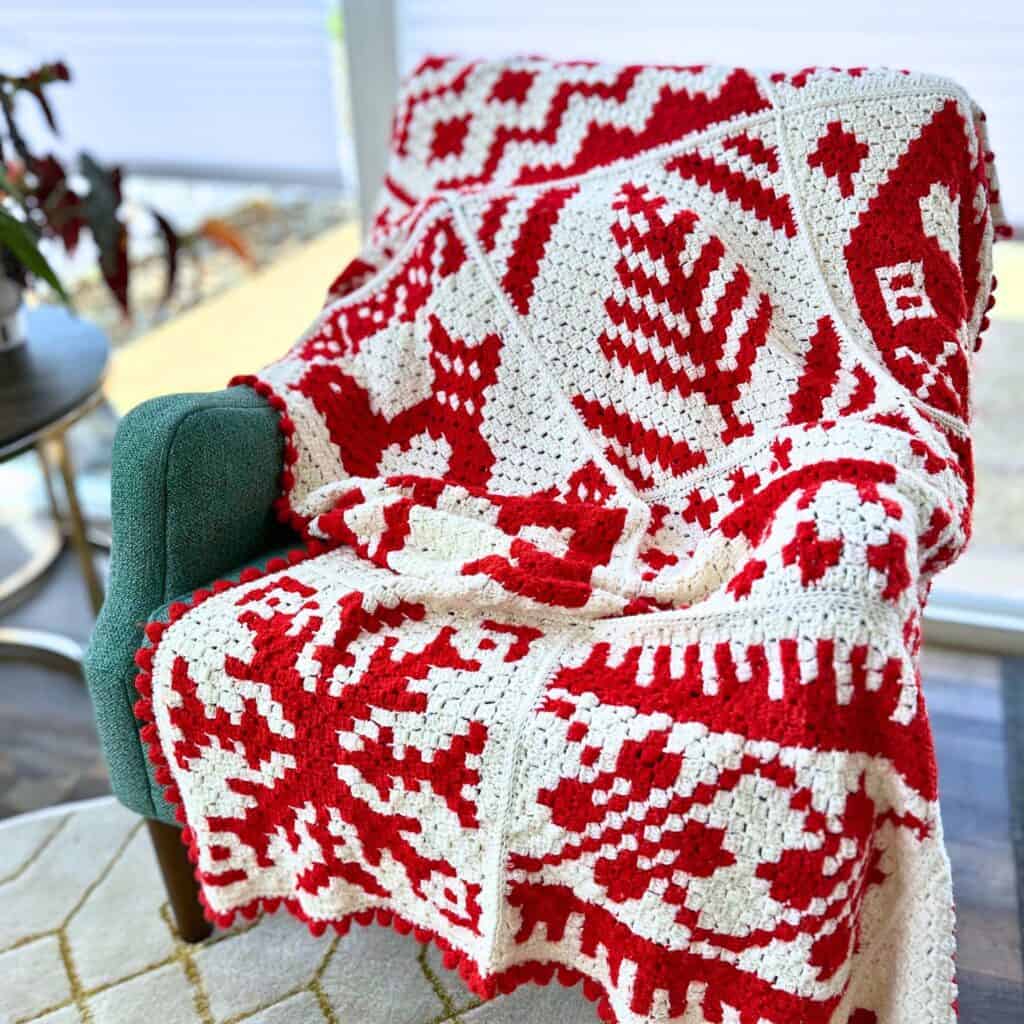 Red and white christmas crochet blanket displayed on green chair