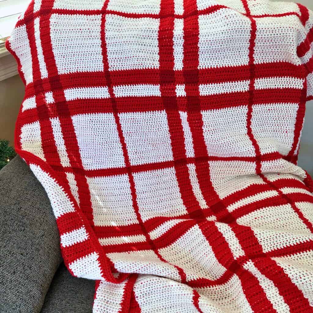Handmade red and white crochet plaid blanket for Christmas decor.