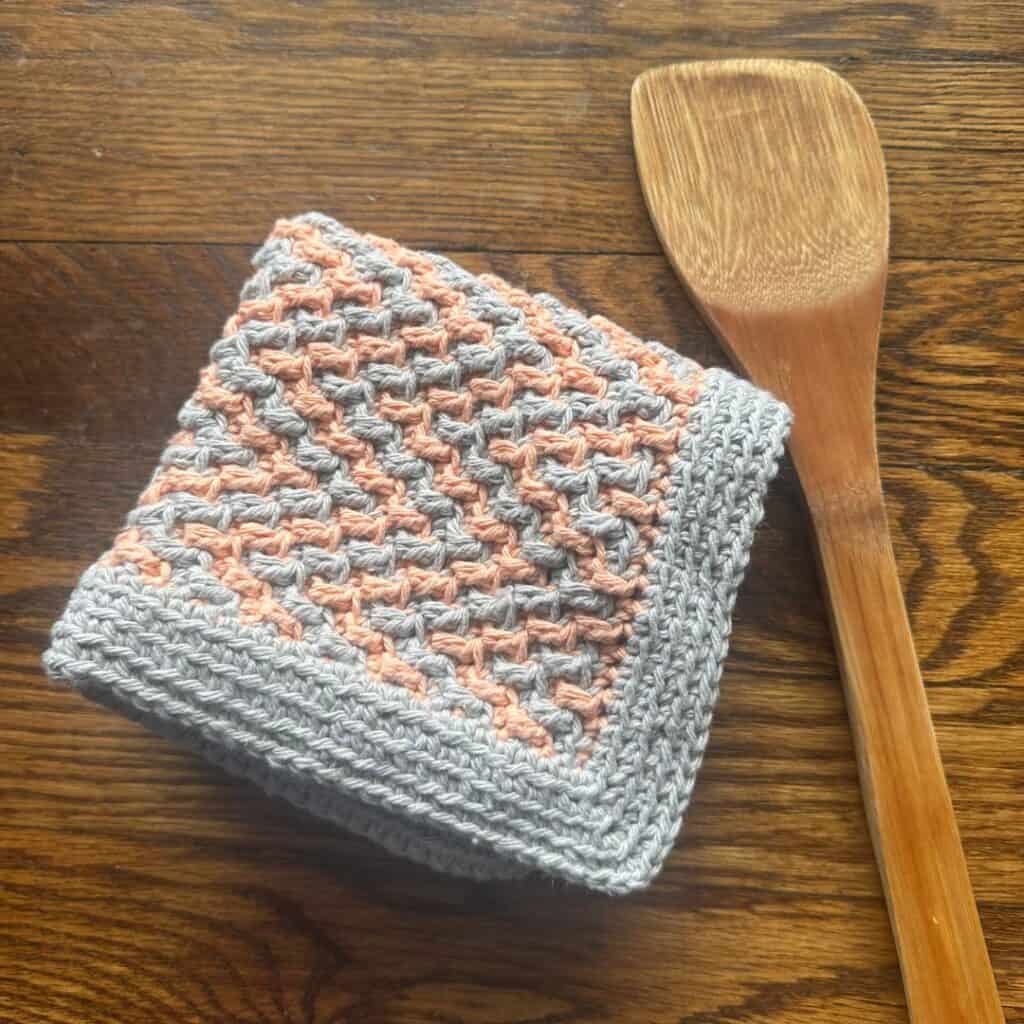 Cute crochet cat toy holder with a braided design and plush toys inside.