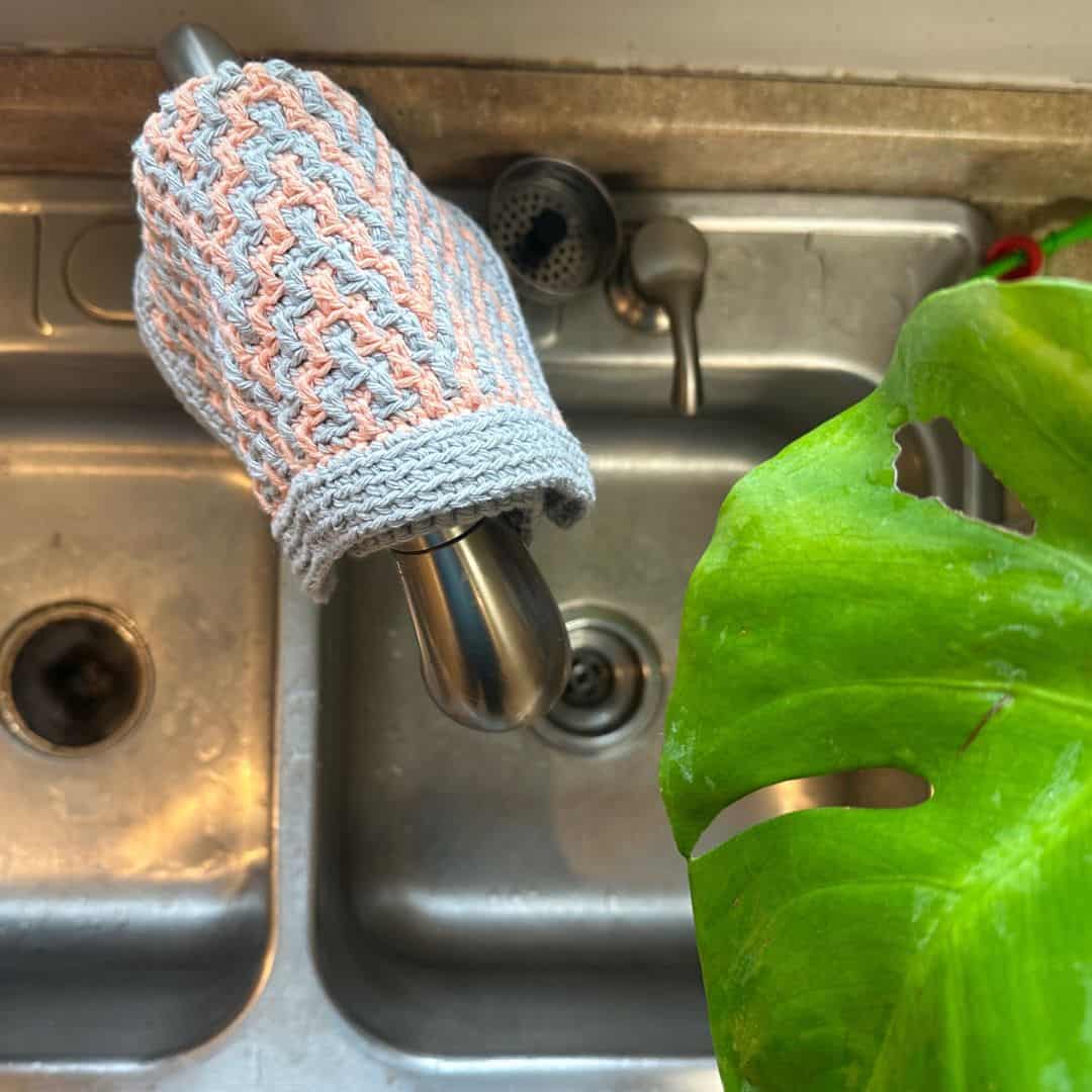 Cute crochet cat toy holder with a braided design and plush toys inside.