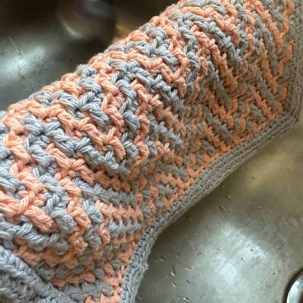 Cute crochet cat toy holder with a braided design and plush toys inside.