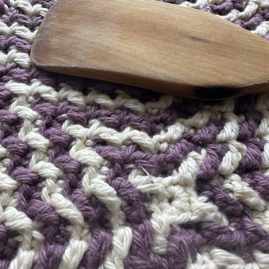 Close-up of a starburst mosaic crochet washcloth with purple and white yarns.