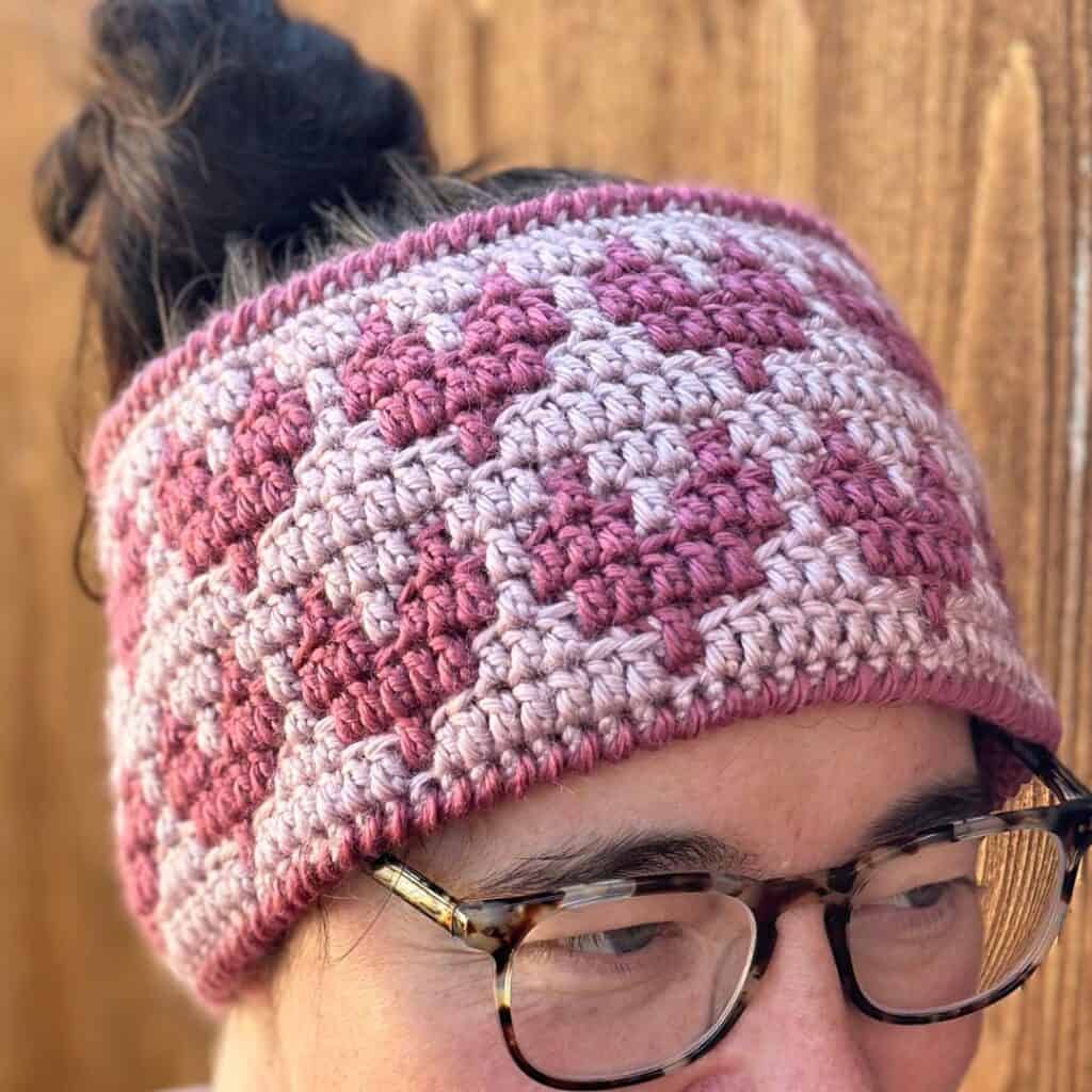 Handmade crochet heart ear warmer in pink and gray yarn, cozy winter accessory.