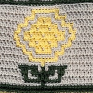 Bright yellow sunflower mosaic crochet design on textured background.