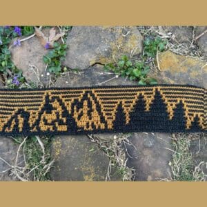 Crochet blanket inspired by Black Hills patterns, featuring black and gold stripes. Perfect for cozy.