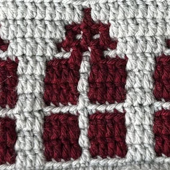 Close-up of a festive crochet mosaic pattern with red and white yarns.