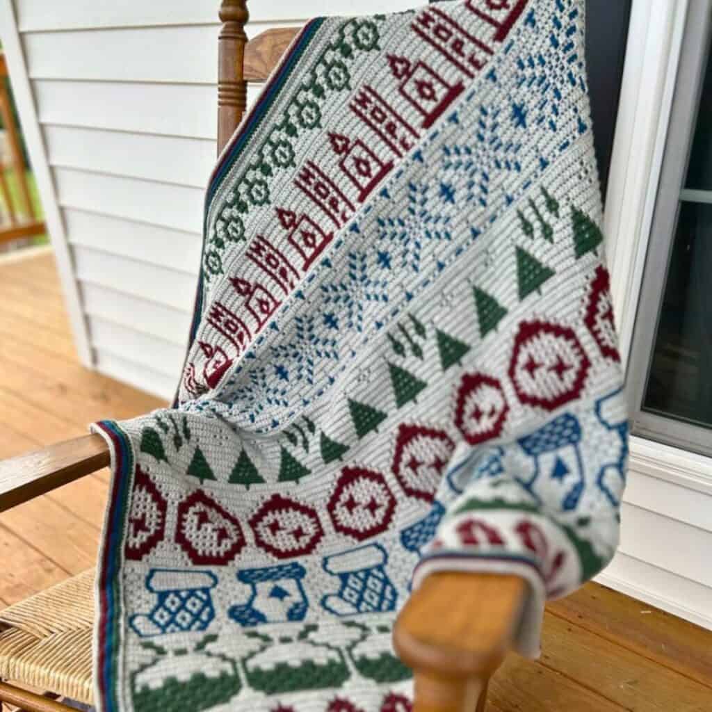 Decorative crochet blanket with holiday-themed mosaic pattern in red, green, and blue.