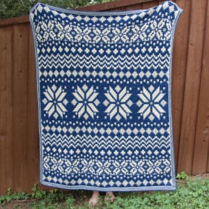 Beautiful blue and white Nordic star mosaic crochet blanket displayed outdoors.