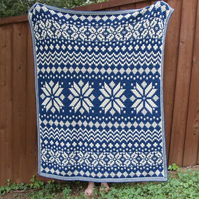 Beautiful blue and white Nordic star mosaic crochet blanket displayed outdoors.