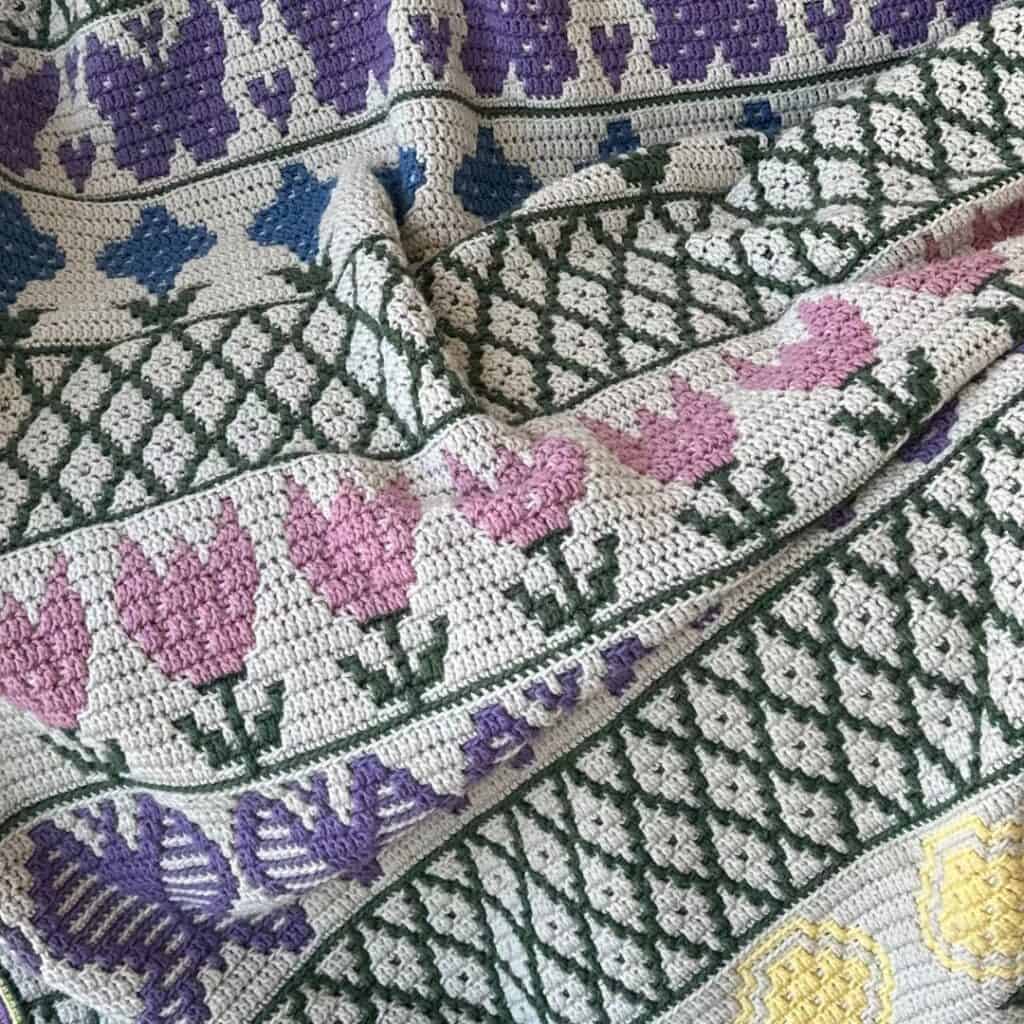 Beautiful mosaic flower garden blanket with vibrant pink, purple, yellow, and green floral patterns.