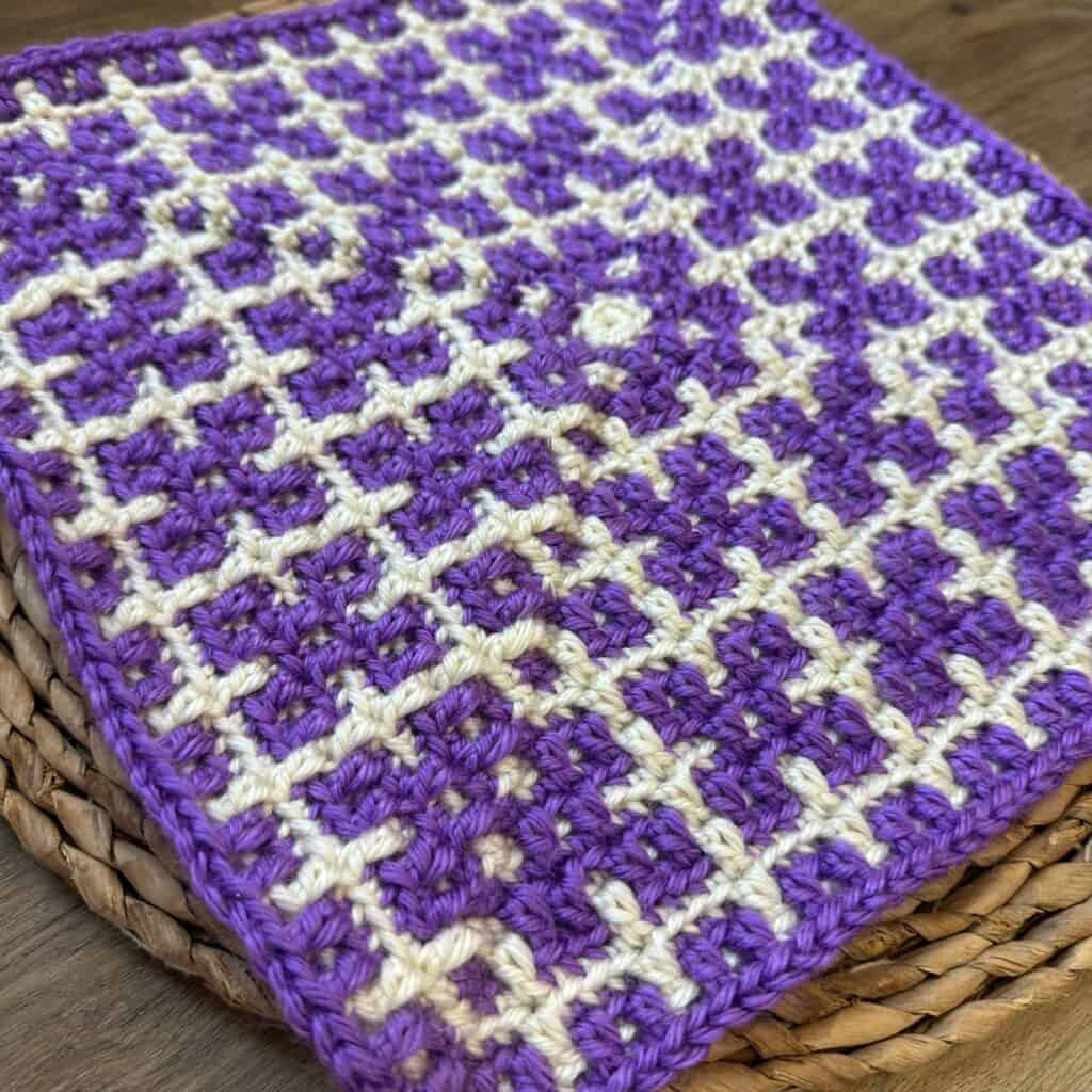 Crochet mosaic square featuring purple and white colors, perfect for blankets or home decor projects.