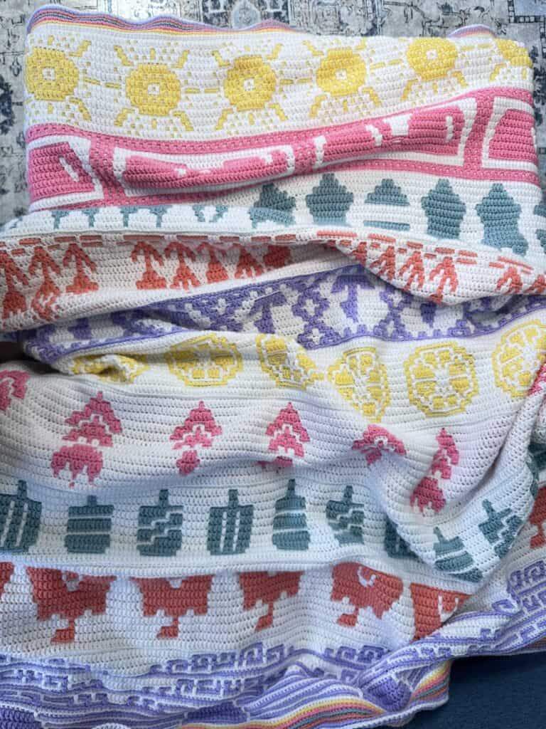 Bright and colorful mosaic crochet blanket with floral and geometric patterns. Perfect for summer de.