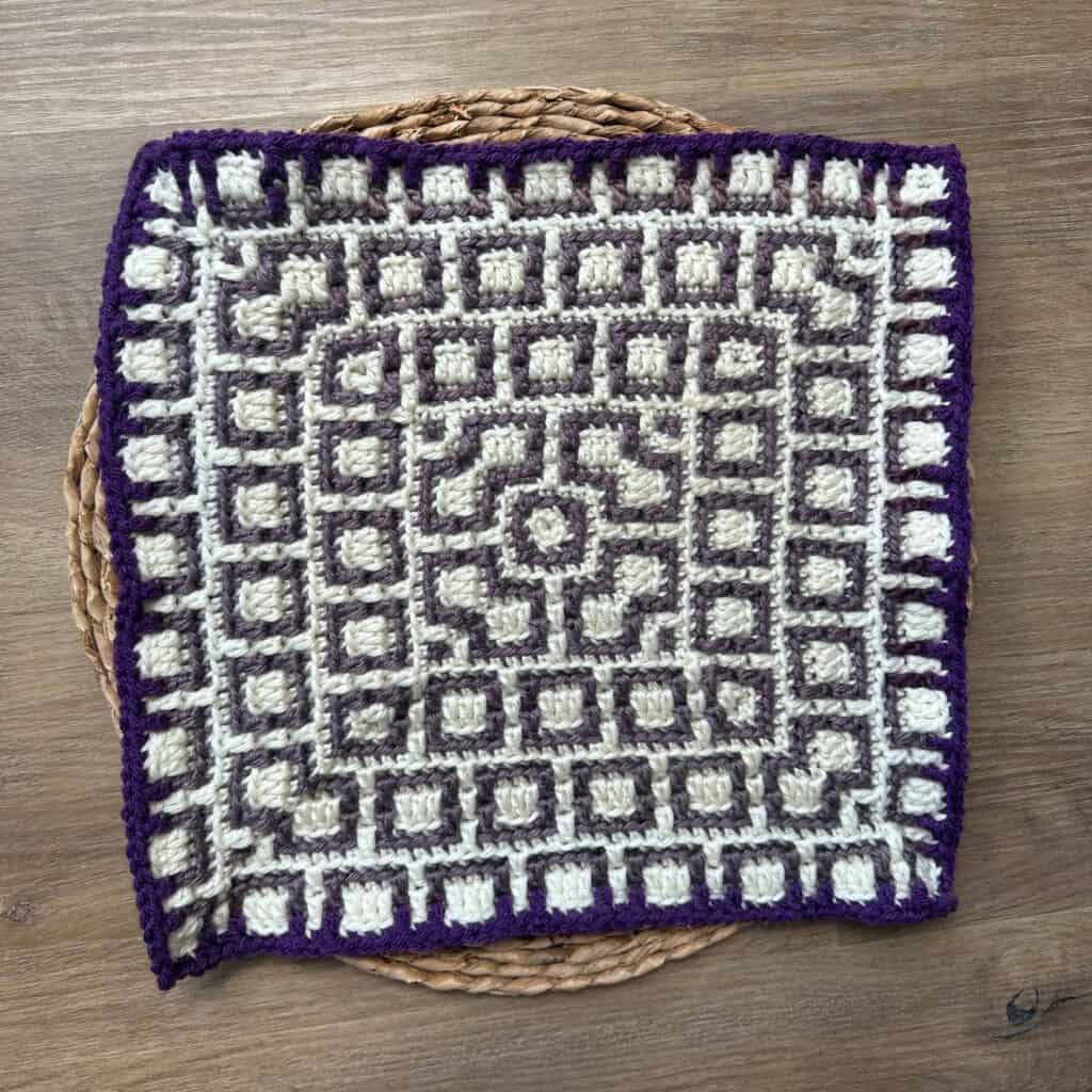 Mosaic crochet square with purple border and intricate geometric design, perfect for creative croche.