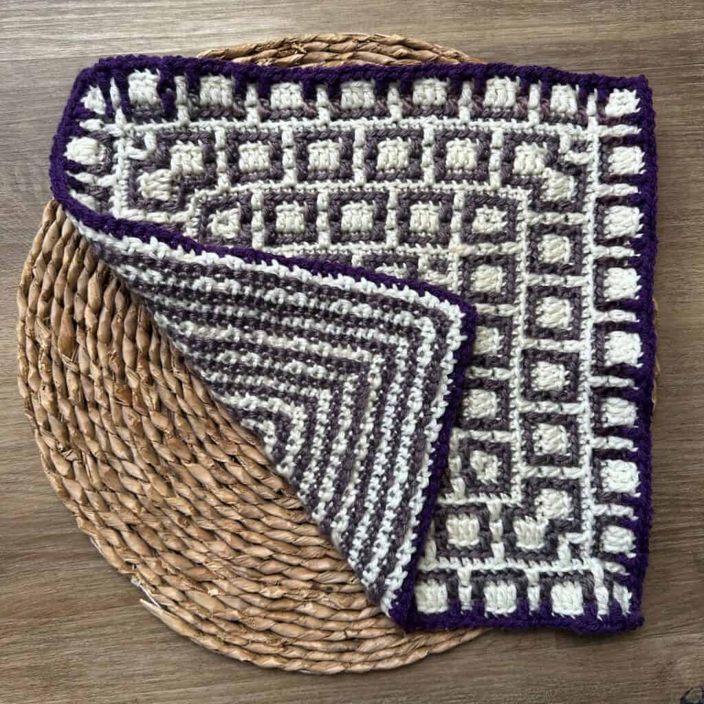 Handcrafted crochet mosaic square rug with geometric pattern in purple and white.