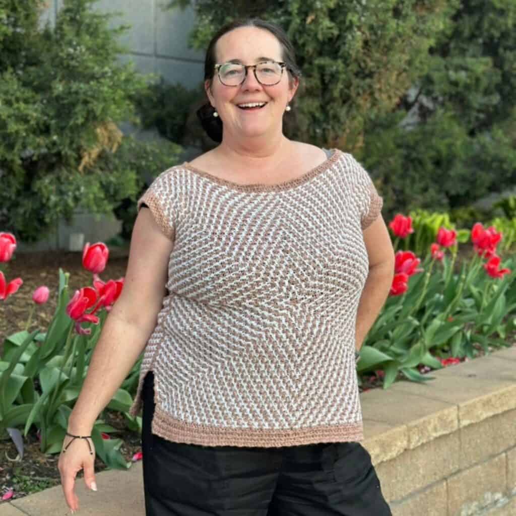 Erin wearing the Mosaic Starburst crochet sweater tee outdoors with tulips in the background.