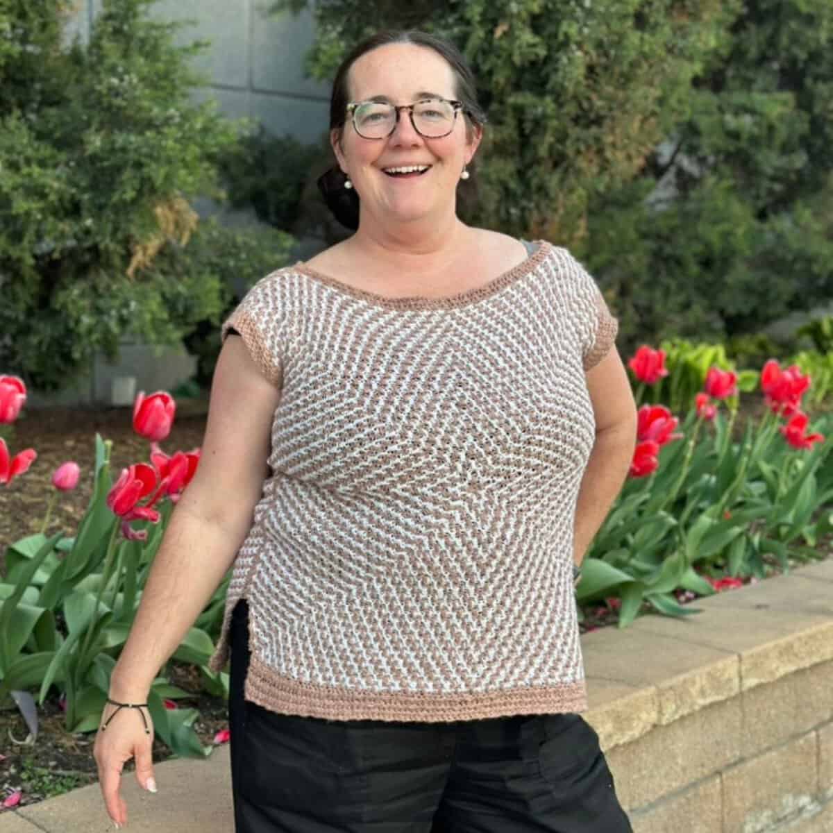 Erin wearing the crochet Mosaic Starburst Tee outdoors with red tulips in the background.