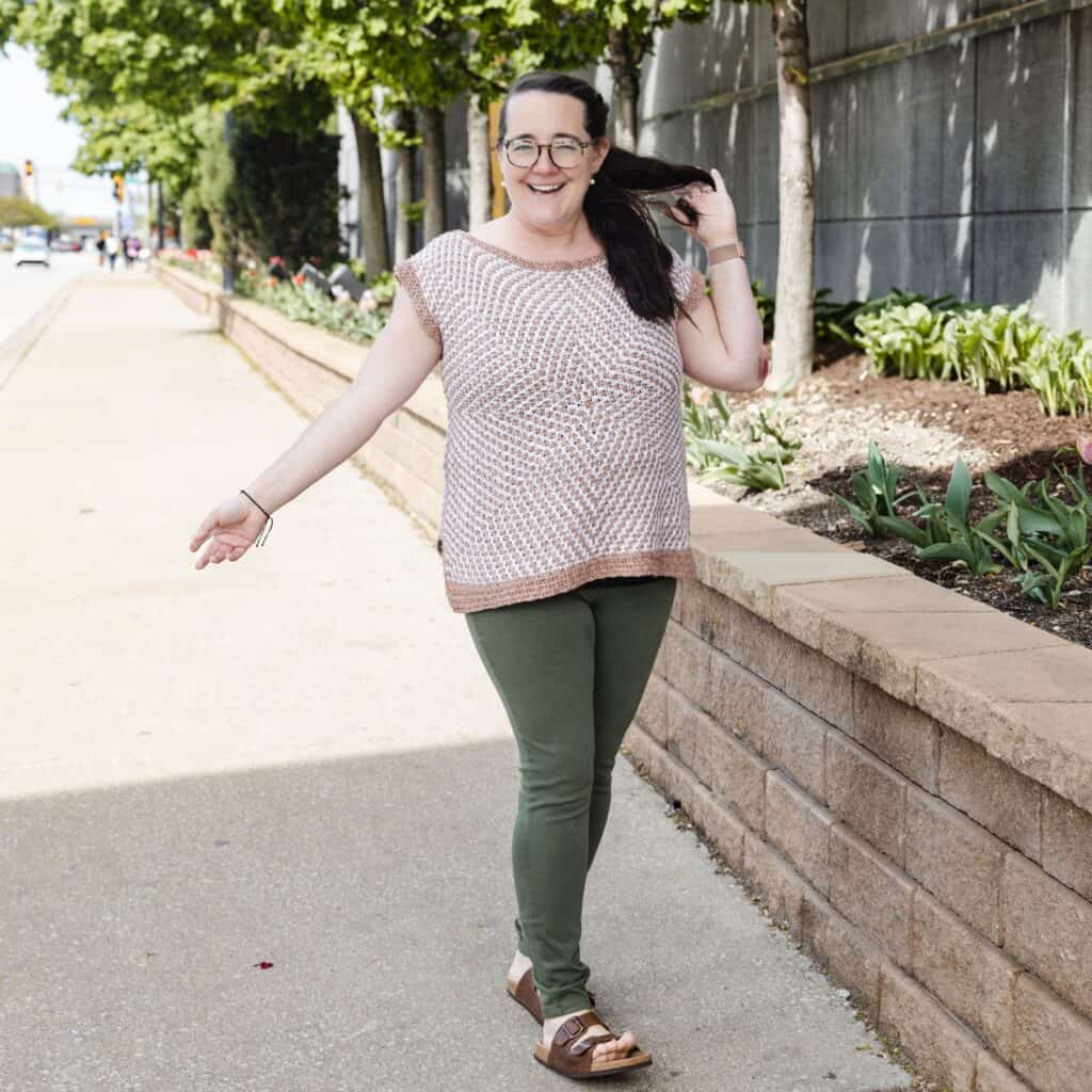 Erin wearing the Mosaic Starburst tee on a city street, smiling and walking.
