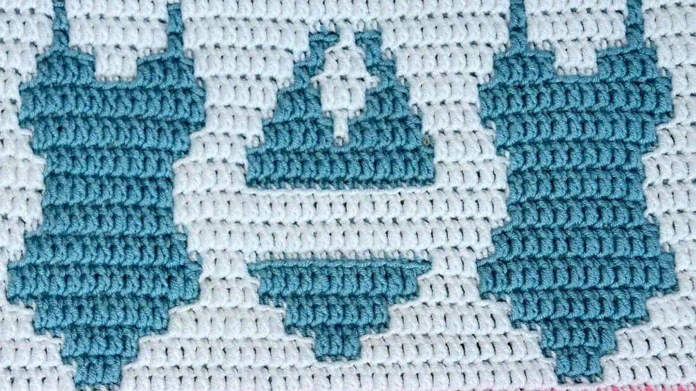 Close-up of a blue and white crochet blanket strip with swimsuit motifs
