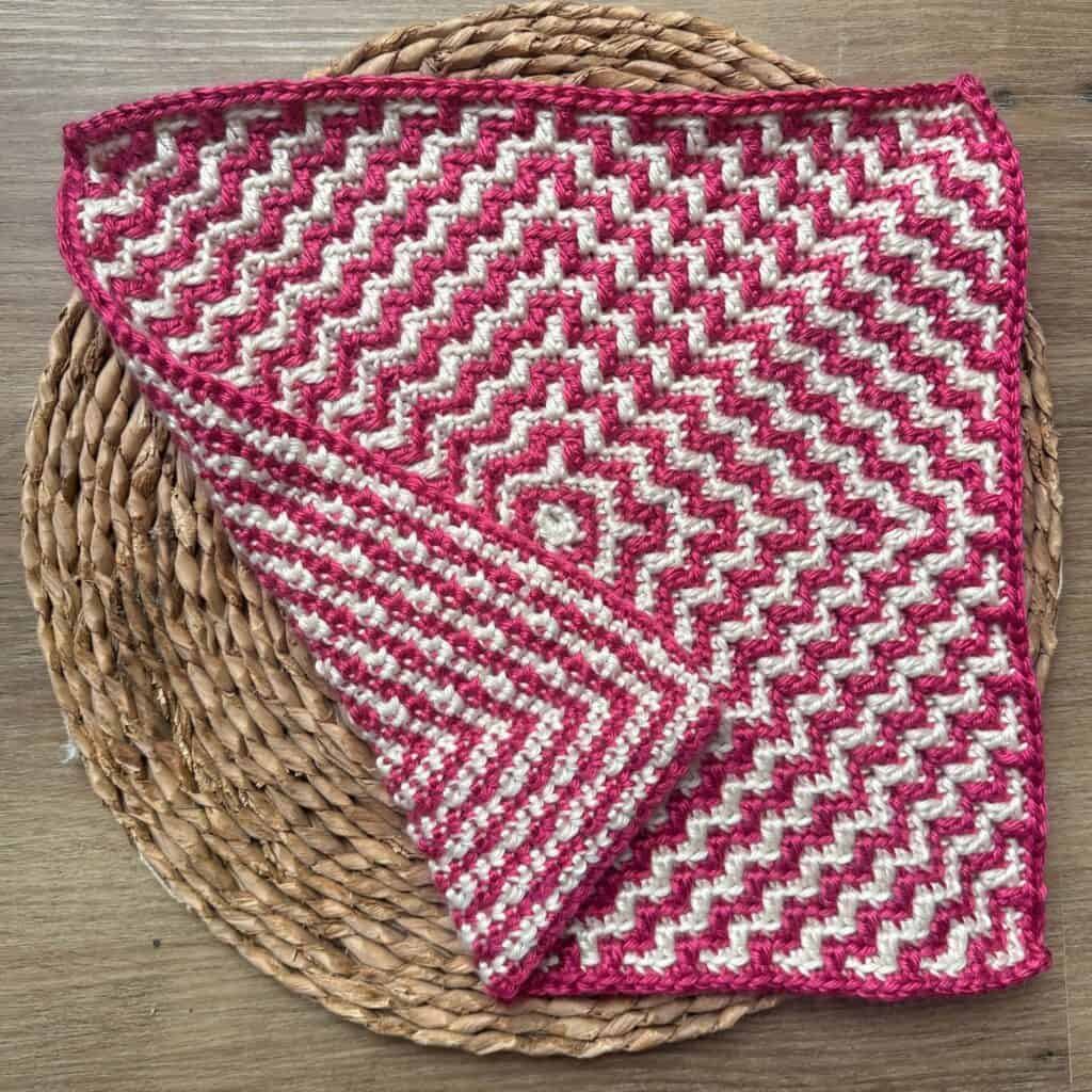 Mosaic crochet square with pink and white ripple pattern, displayed on a woven mat. Perfect for croc.